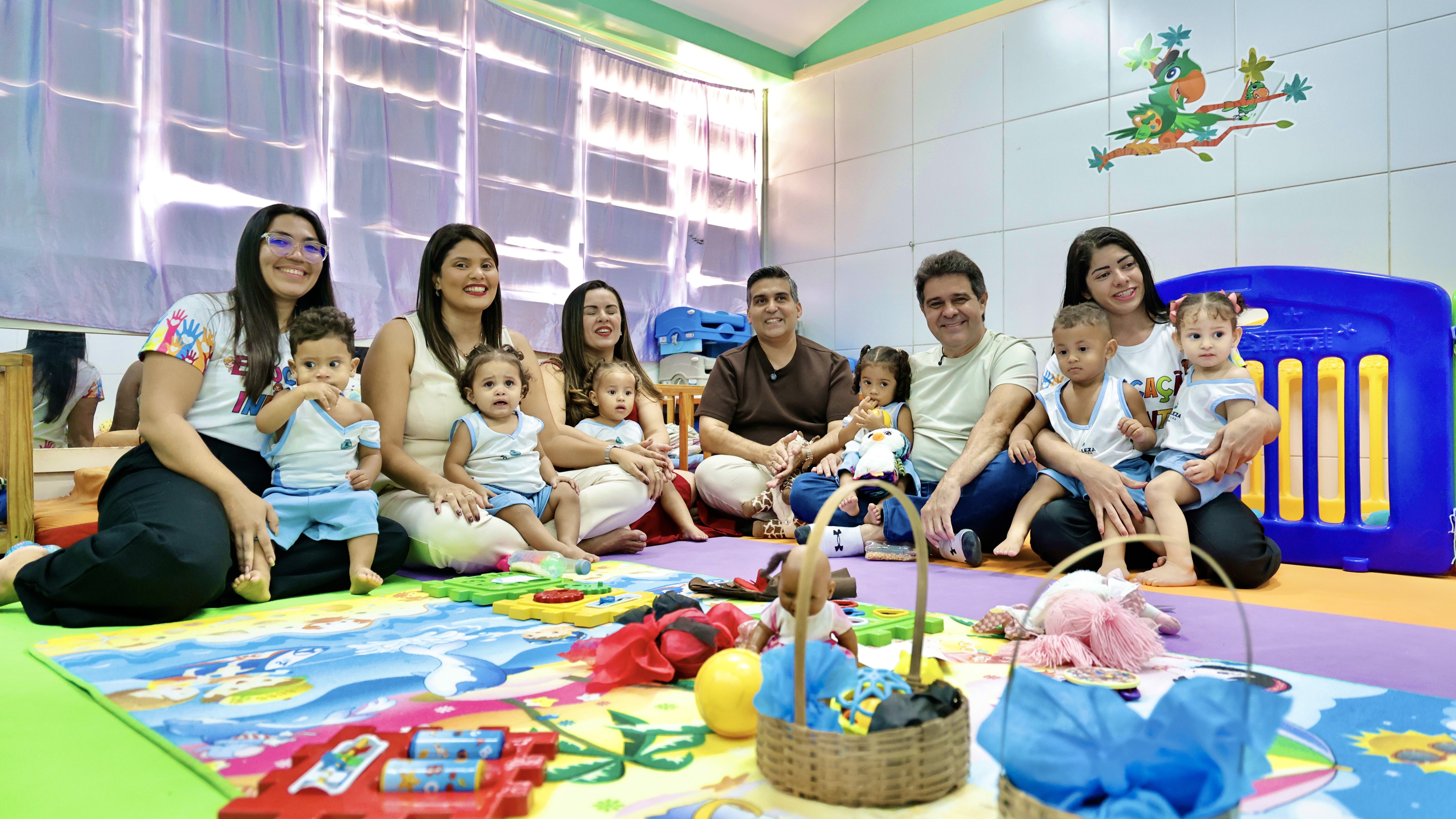Prefeito Evandro, um grupo de professores e alunos do CEI sentados no chão de uma sala de aula